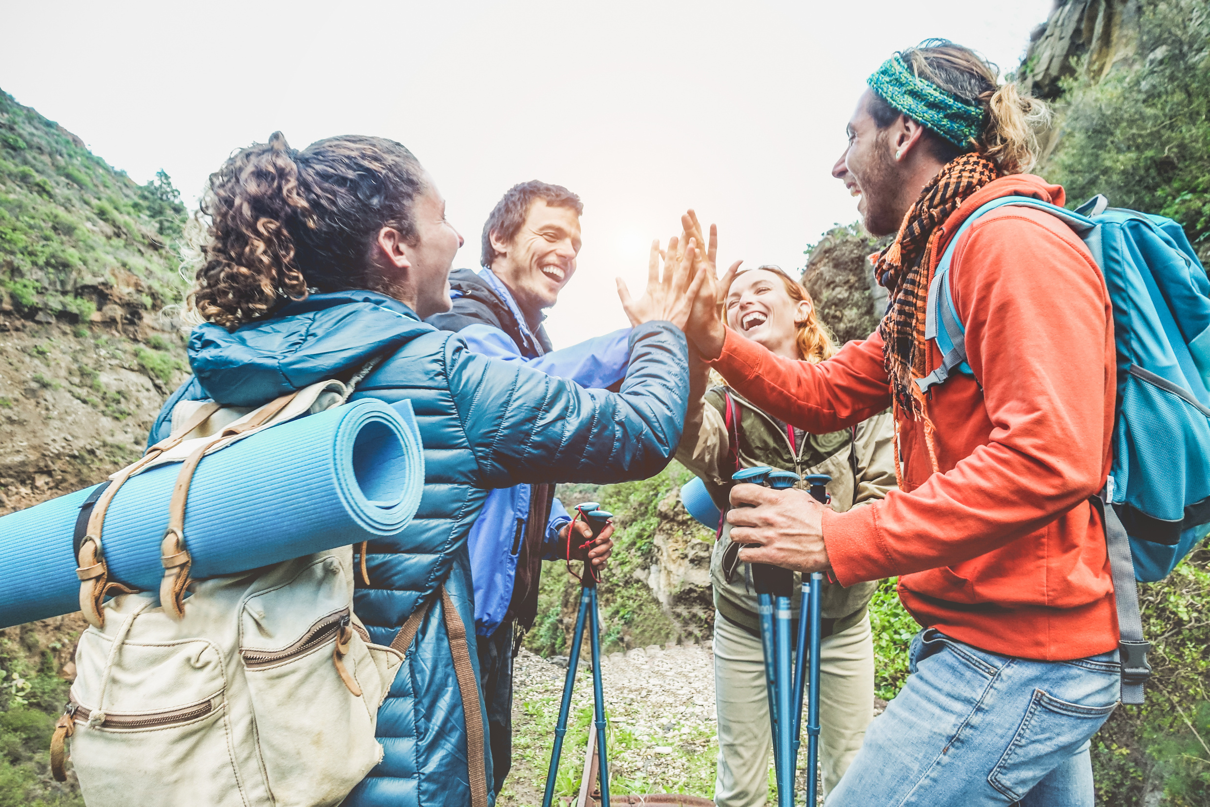 Group of happy trekkers stacking hands outdoor - Young hiker friends supporting each others - Survival, team, travel, success and adventure concept - Focus on hands